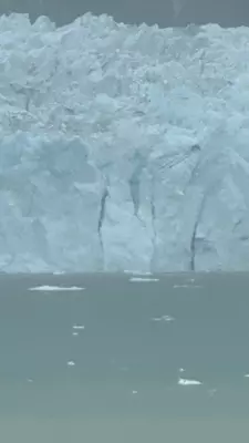 A glacier in the ocean on an overcast day.
