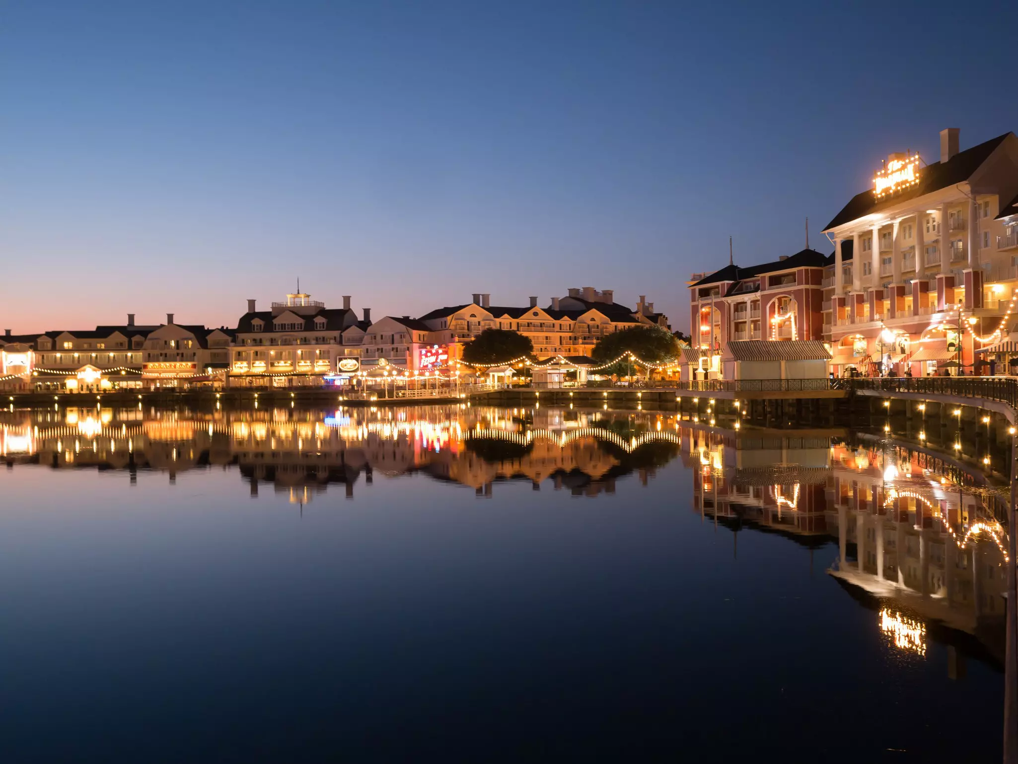 A lakefront promenade lined with mansion-like buildings lit up in twilight