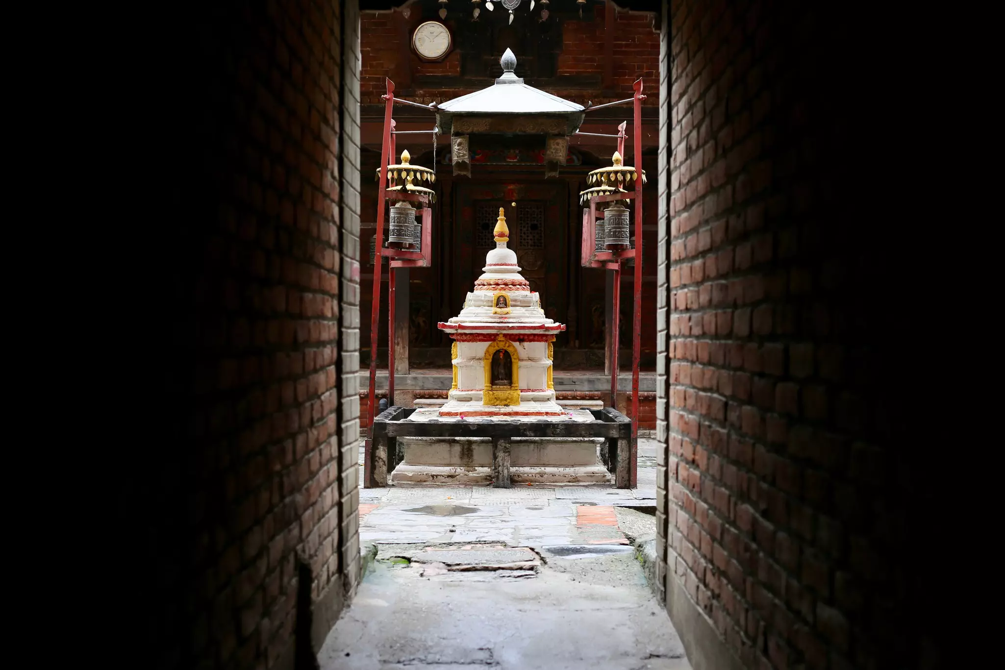 An alleyway leads to a hidden courtyard containing a chaitya (stupa) in Patan, Nepal.