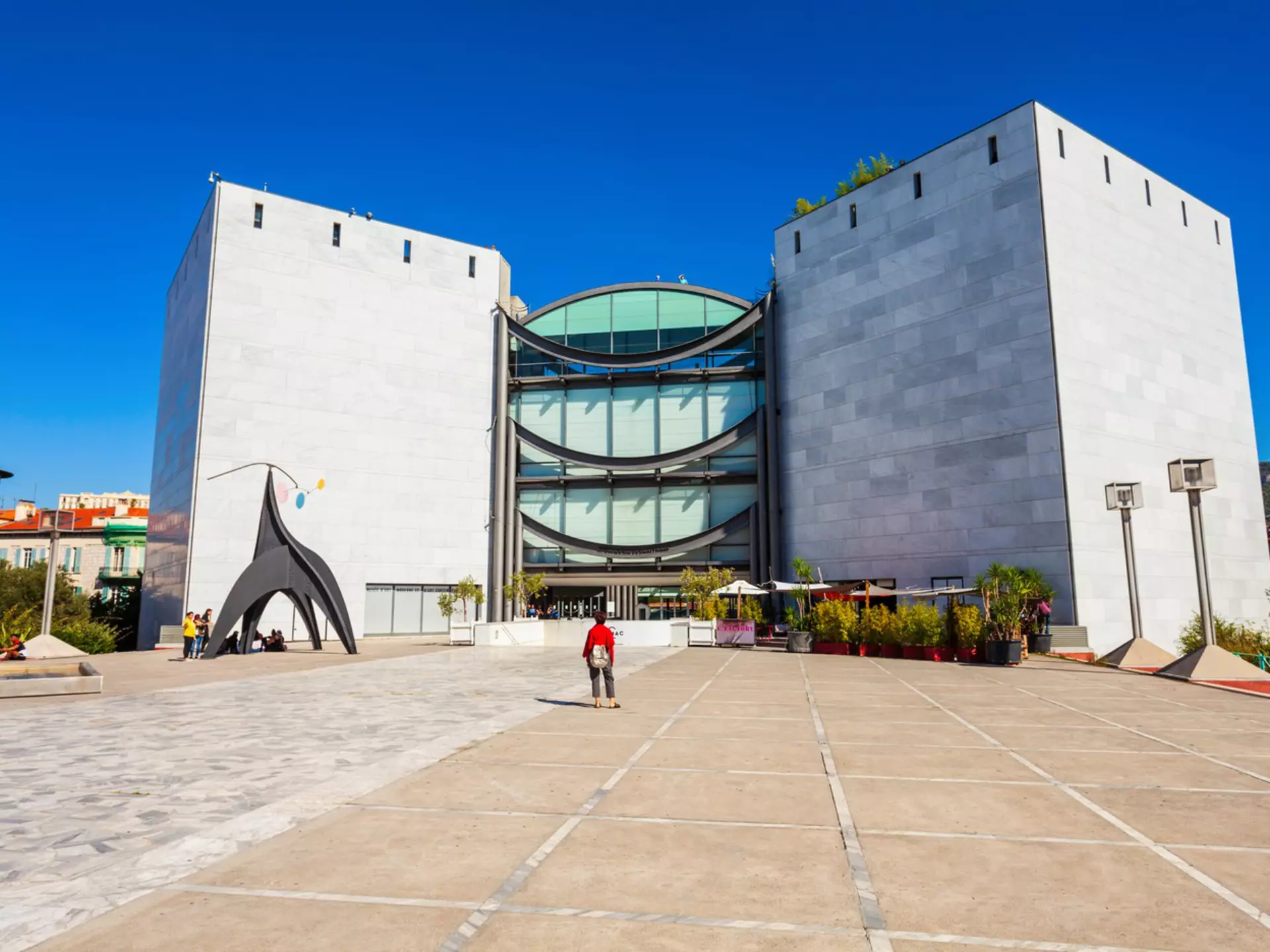 A solo figure stands looking towards a large modern building that houses Nice's Museum of Modern and Contemporary Art