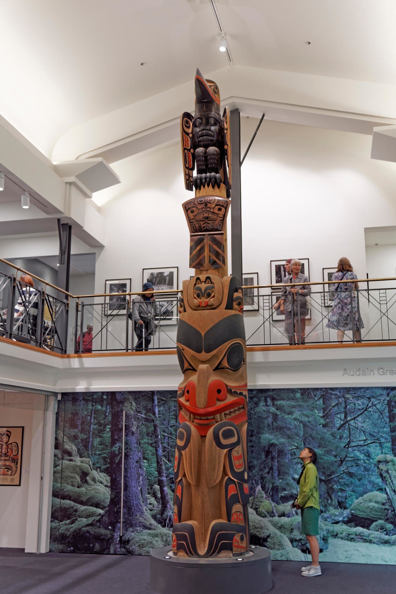 Young woman looking up at the James Hart totem pole in the Gallery of Northwest Coast Art, Vancouver, British Columbia, Canada.