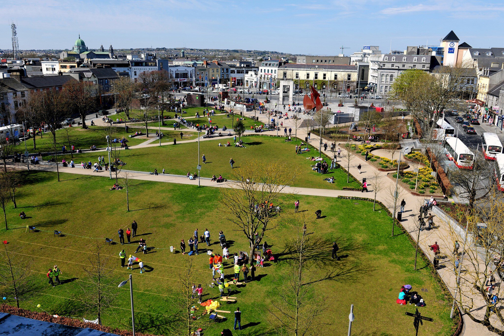 Aerial of Eyre Square in Galway City, Ireland.  People on the meadows and city in the background. 