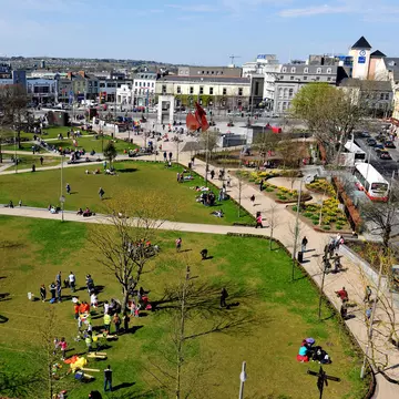 Aerial of Eyre Square in Galway City, Ireland.  People on the meadows and city in the background. 