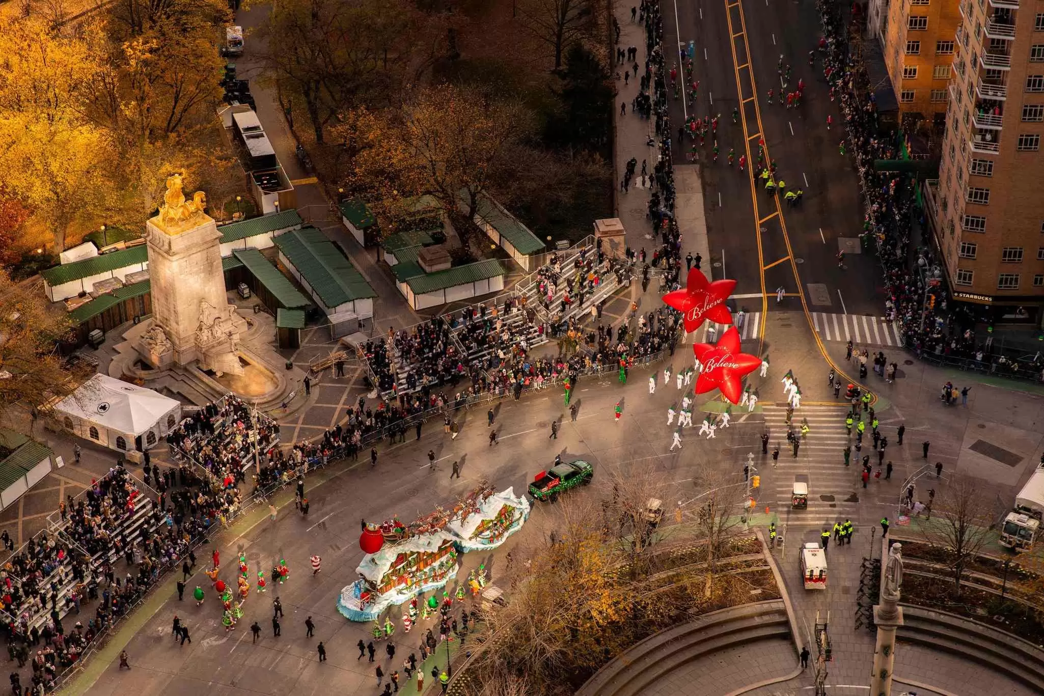 A series of colorful character balloons make their way down a city street in a parade: The Macy’s Thanksgiving Day Parade from above. Mandarin Oriental, New York 