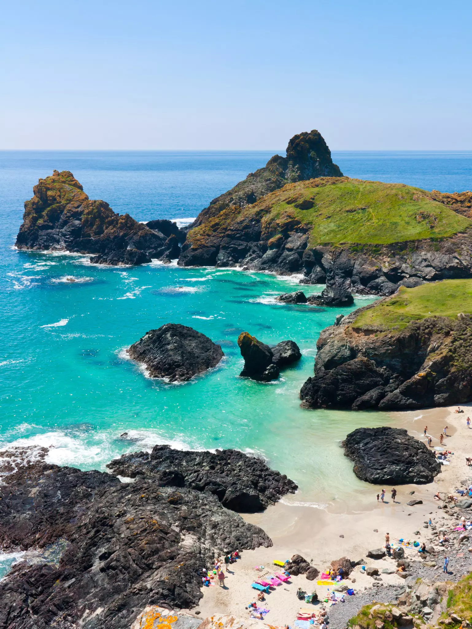 A gorgeous rocky cove lapped by turquoise water. Several colorful kayaks are lined up ready to rent.