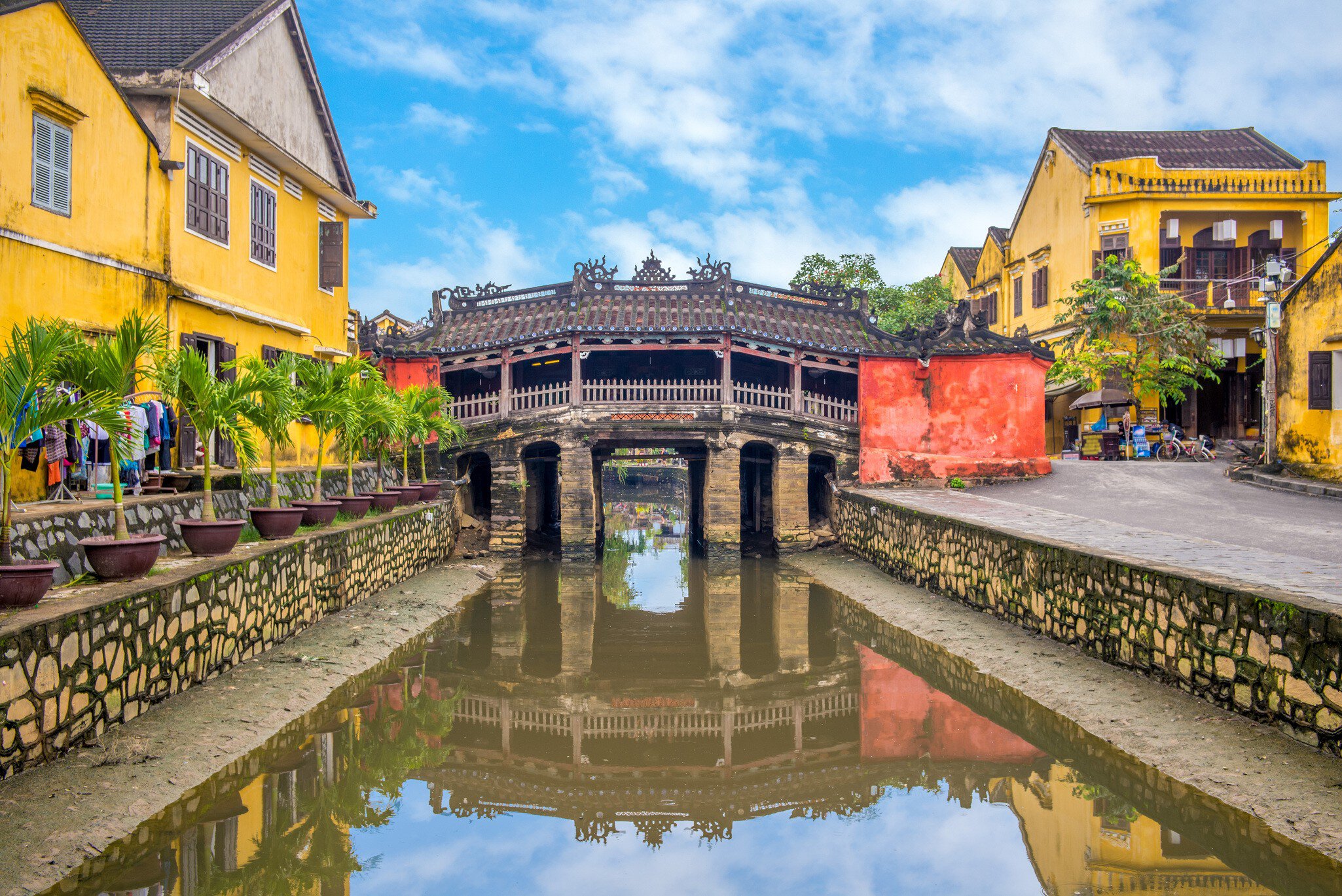 An 18-meter-long footbridge called The Japanese Bridge or Lai Vien Kieu, overlooking the water on a sunny day in Hoi An, Vietnam.