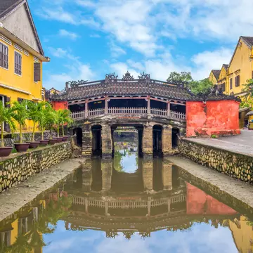 An 18-meter-long footbridge called The Japanese Bridge or Lai Vien Kieu, overlooking the water on a sunny day in Hoi An, Vietnam.