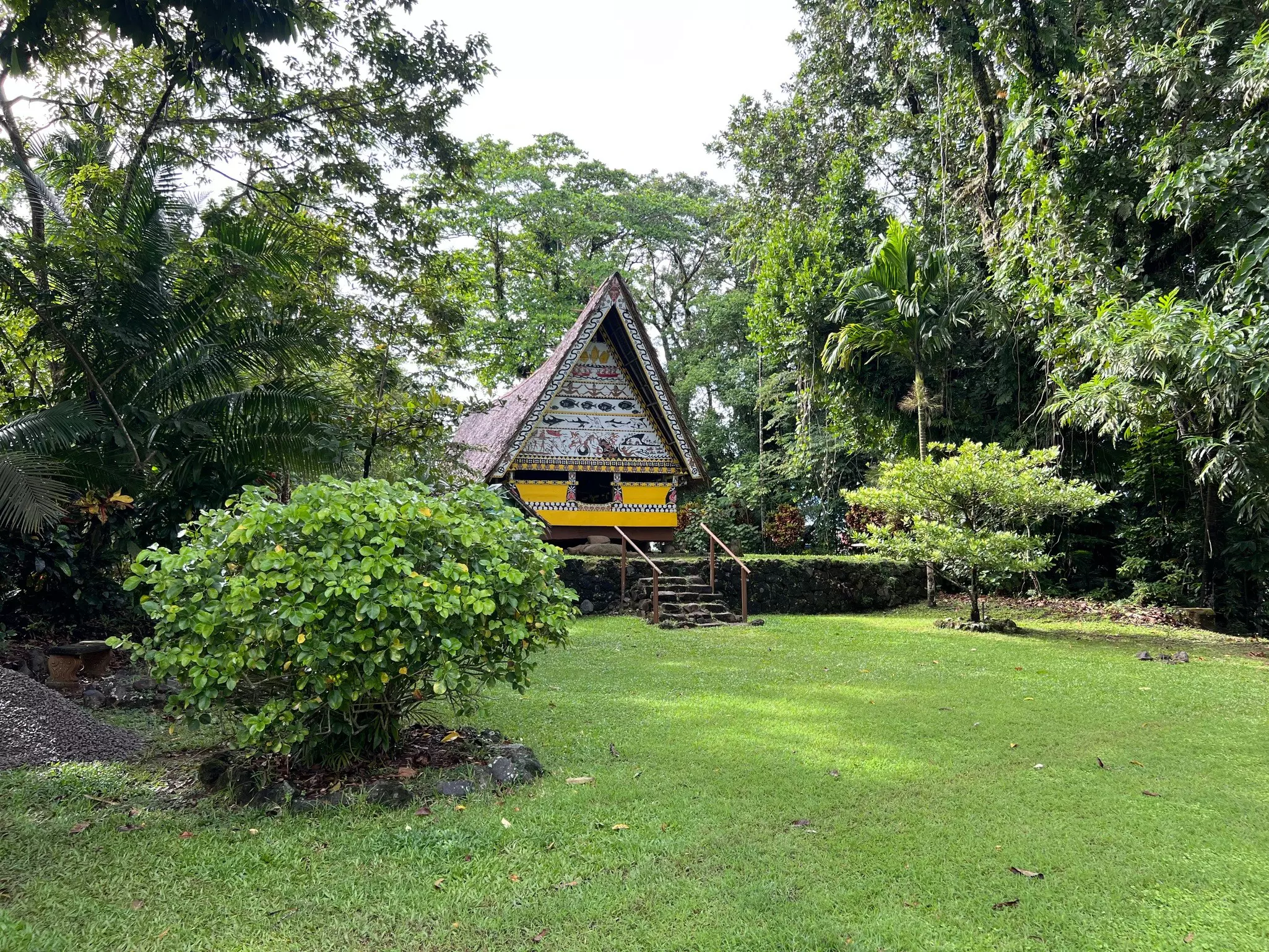 A restored bai meeting house at the Belau National Museum in Palau, surrounded by green gardens.