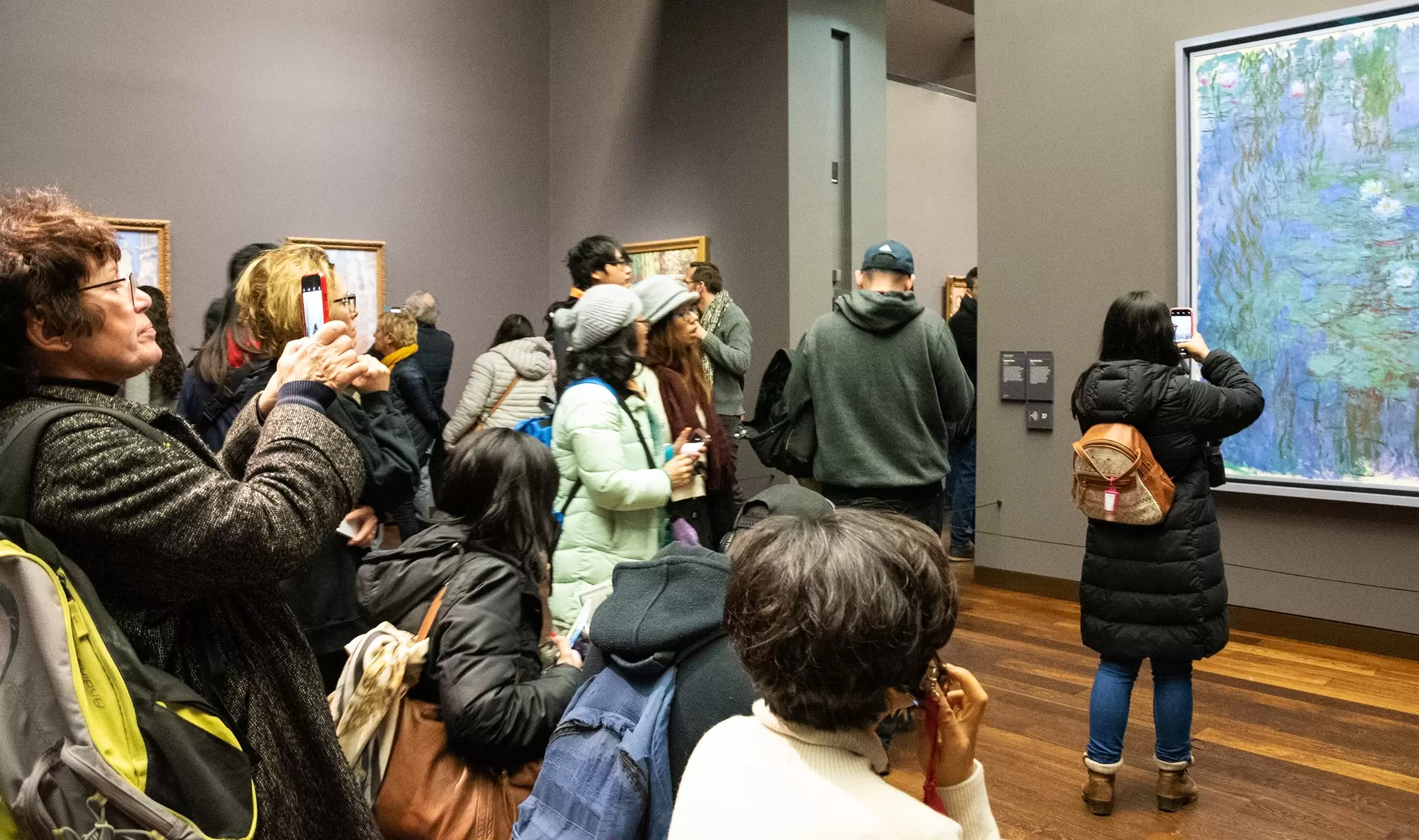 Visitors admire and take photos of Blue Water Lilies by Claude Monet in Musée d'Orsay famous for its impressionist and post-impressionist collections.