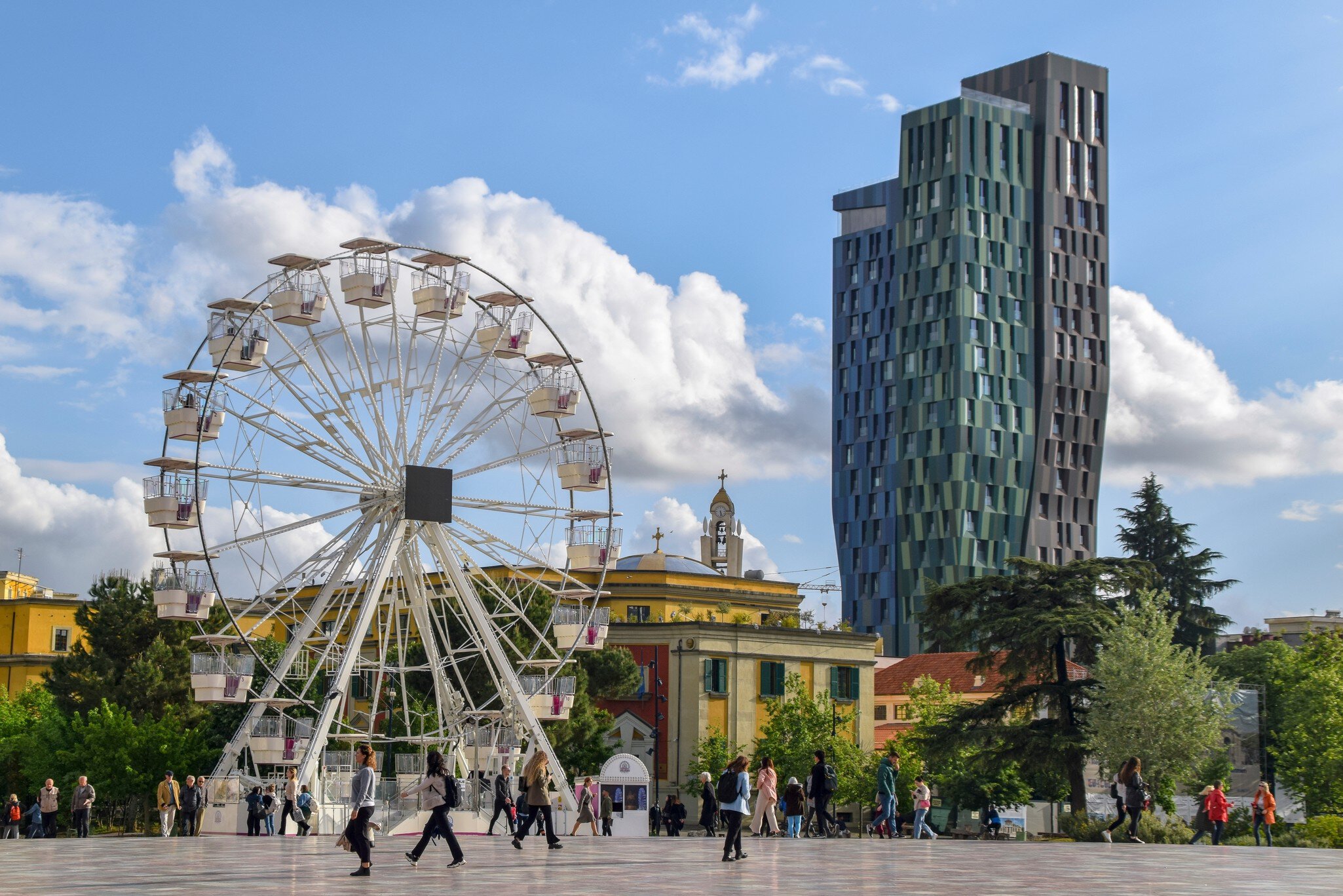Tirana, Albania - April 20 2024:Local people and tourists at the Skanderbeg Square (Sheshi Skënderbej), the main plaza in Tirana, close to the National Theatre of Opera and Ballet of Albania., License Type: media, Download Time: 2026-02-23T19:04:51.000Z, User: rhylton_redventures, Editorial: true, purchase_order: 65050 - Digital Destinations and Articles, job: Lonely Planet, client: Rhianydd Hylton, other: off season