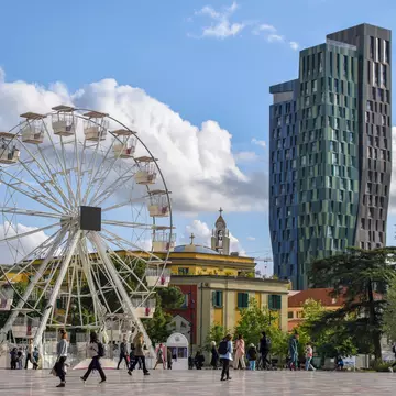Tirana, Albania - April 20 2024:Local people and tourists at the Skanderbeg Square (Sheshi Skënderbej), the main plaza in Tirana, close to the National Theatre of Opera and Ballet of Albania., License Type: media, Download Time: 2026-02-23T19:04:51.000Z, User: rhylton_redventures, Editorial: true, purchase_order: 65050 - Digital Destinations and Articles, job: Lonely Planet, client: Rhianydd Hylton, other: off season