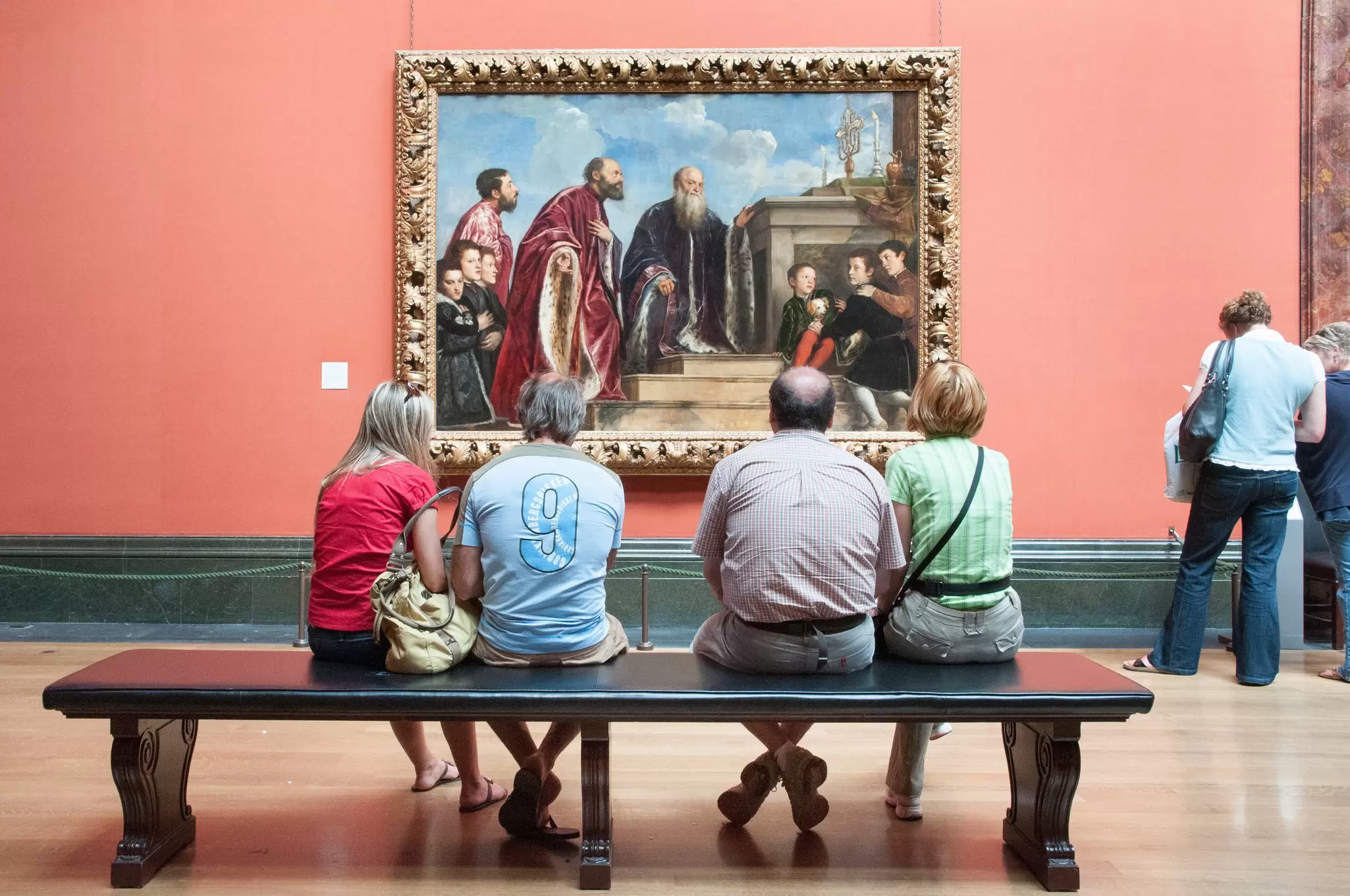 Visitors looking at 'Portrait of the Vendramin Family' by Titian in the National Gallery in London, UK.