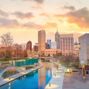 A city skyline at twilight, with a canal leading up to it