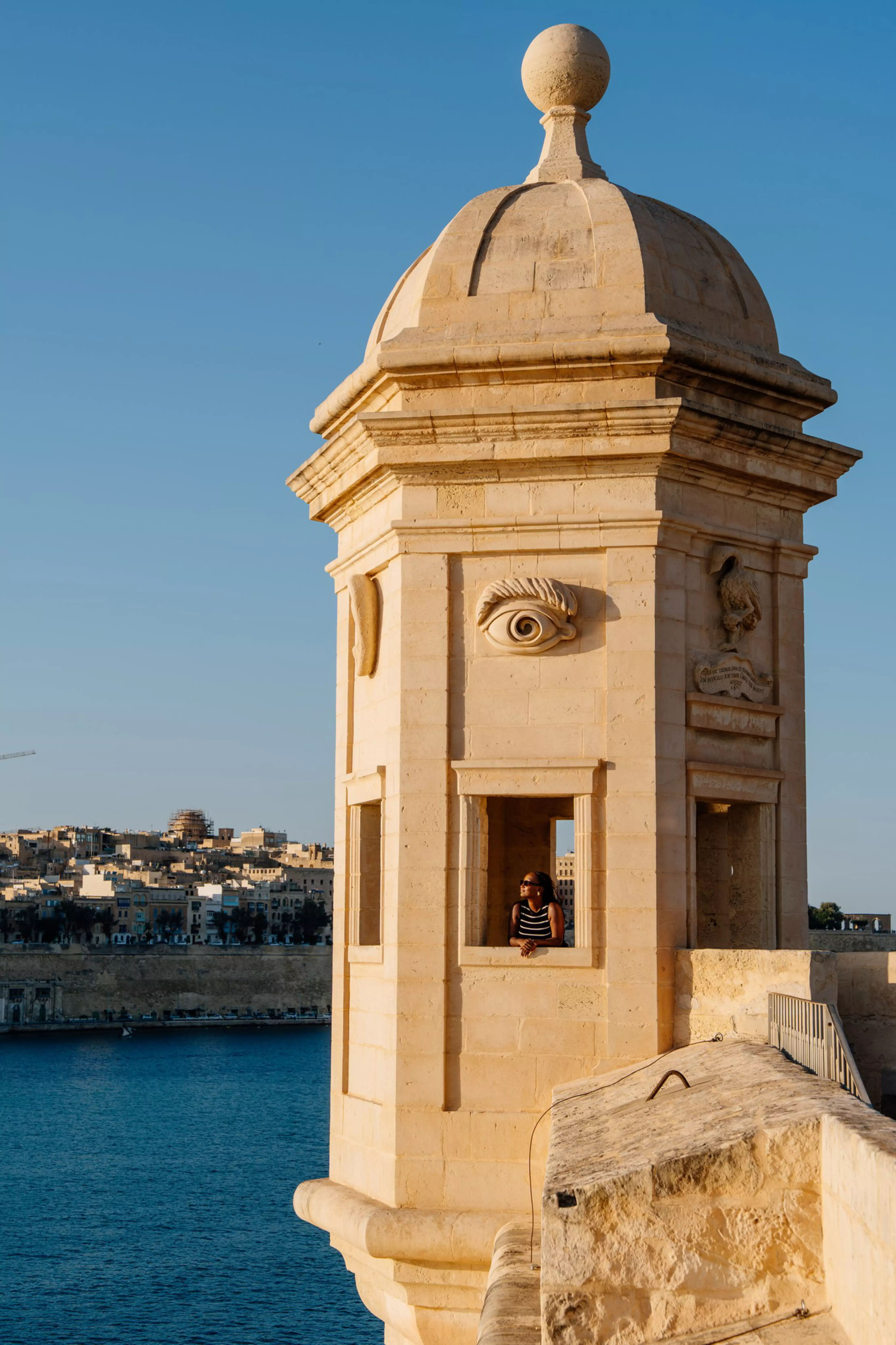 Jacklynn standing at the Gardjola Gardens watchtower (Vedette) in Senglea, Malta, overlooking the Grand Harbour.