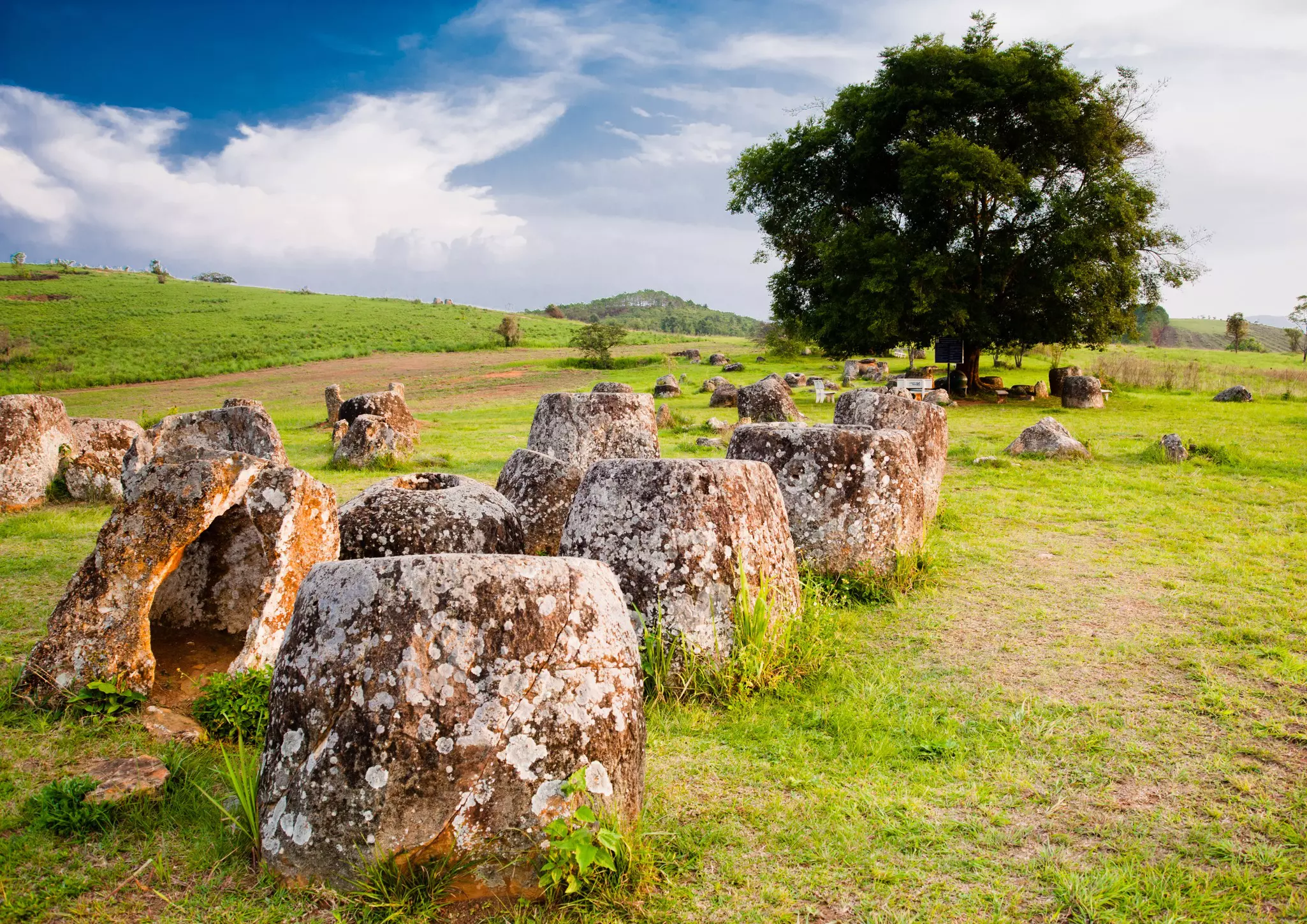 A series of large ancient stone jars in a field.