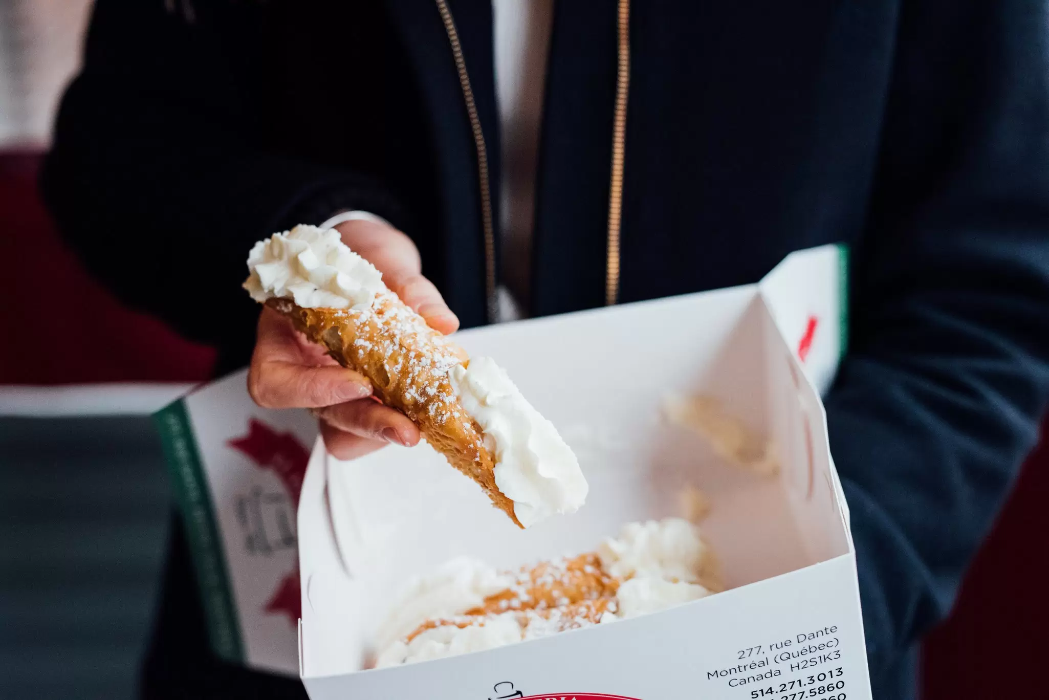 A close-up of a person holding cannoli pastries, Pasticceria Alati-Caserta, Montréal