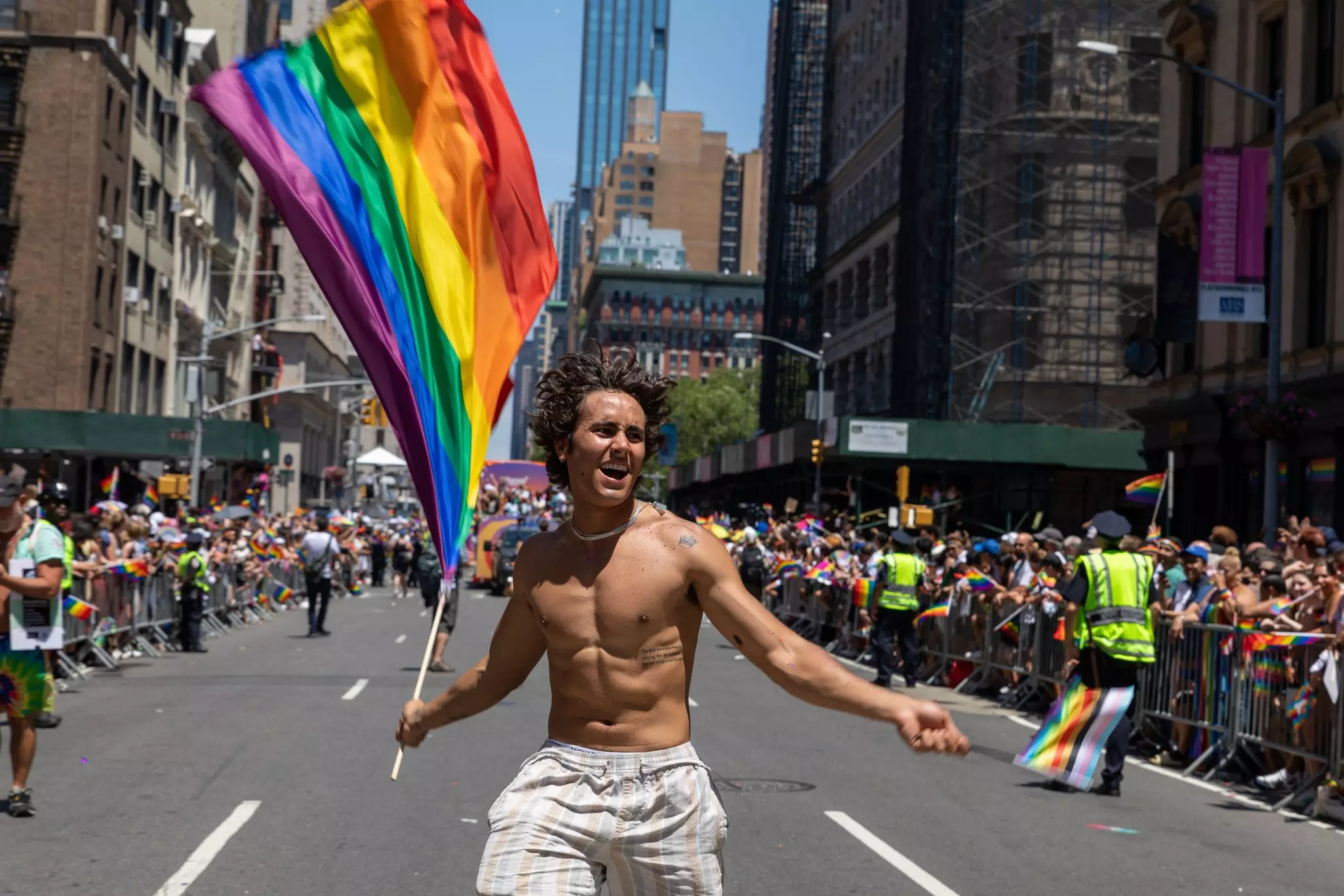 Man carries rainbow flag while people celebrate at the Pride Month Parade on the streets of New York City, USA