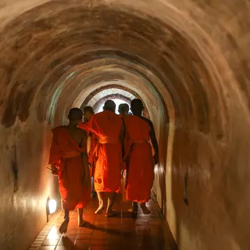 A group of monks walking inside tunnel Wat Umong or "Tunnel temple" . Wat Umong Suan Phutthatham. Chiang Mai, Thailand.
