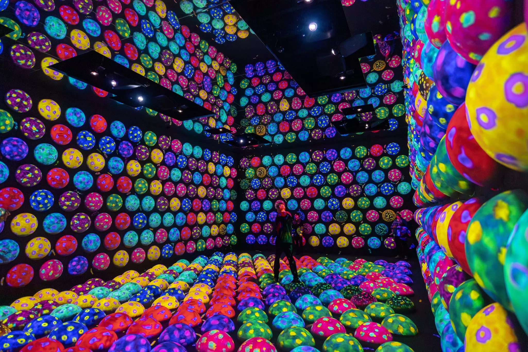 A person in the middle of an installation of multicolored balls in Tokyo.