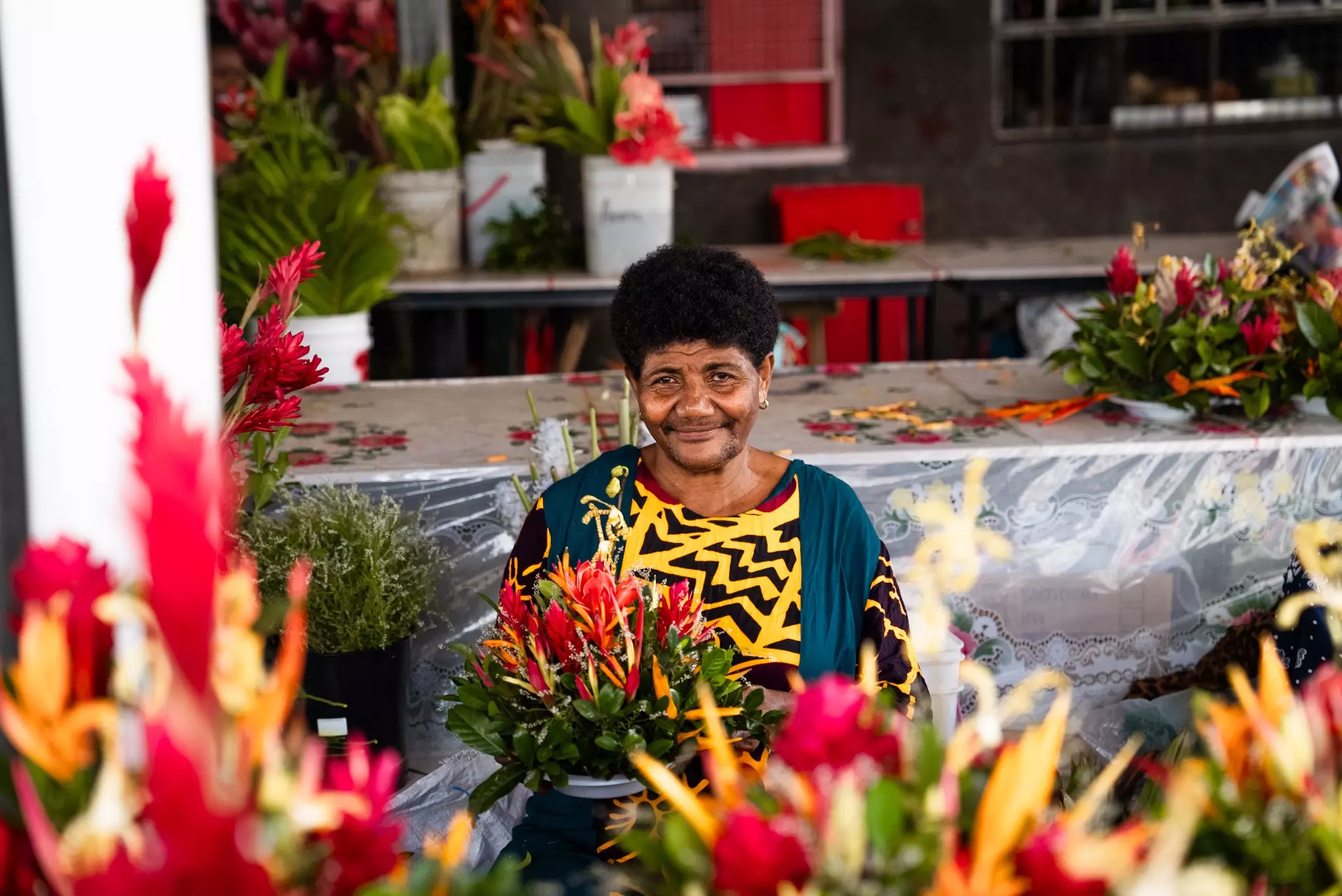 A flower seller surrounded with pink, yellow and green bouquets in the commercial district in Suva. Alipate Laveti for Lonely Planet
