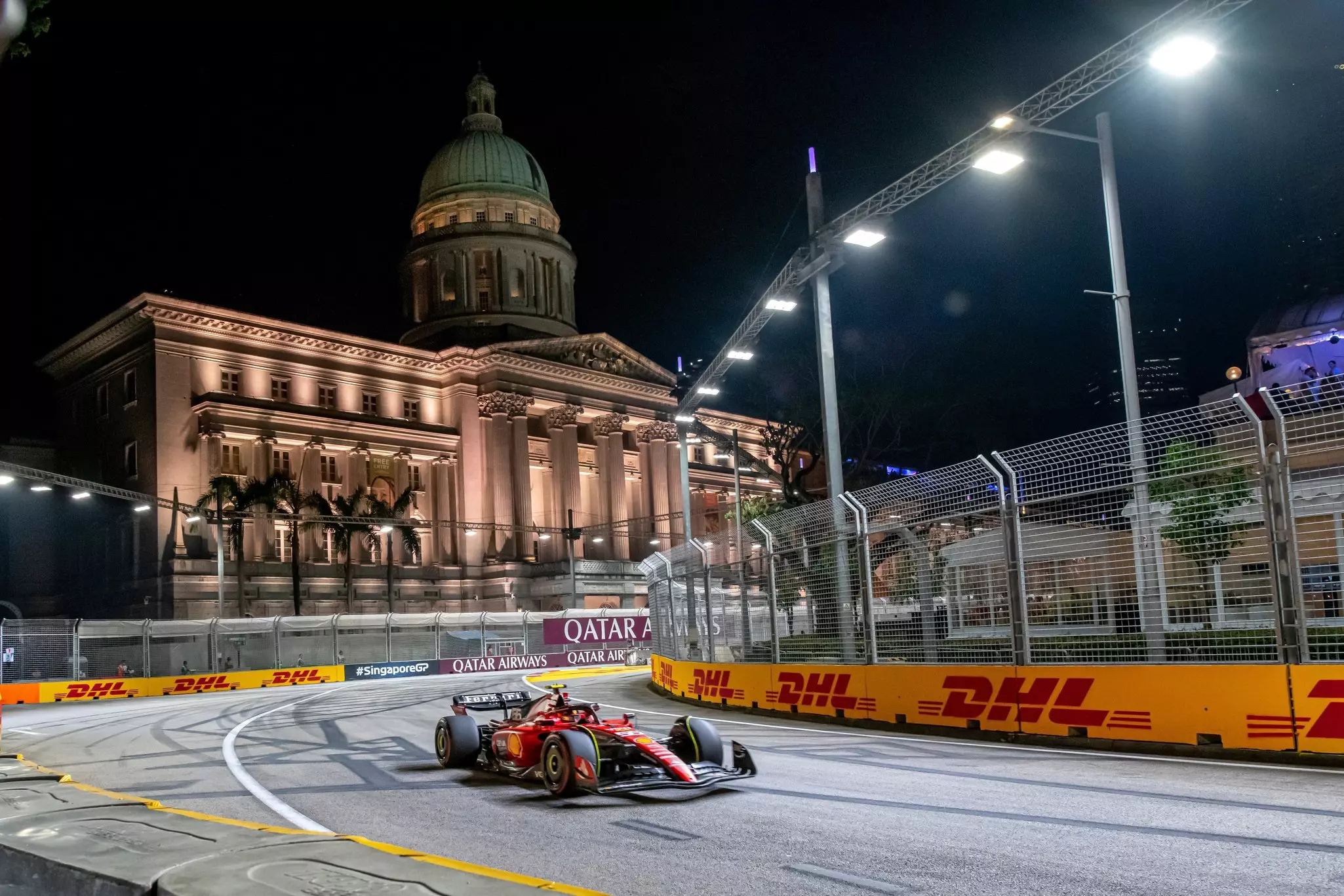 A race car makes a turn on a city street at night in front of a large historic building with beautiful illumination.