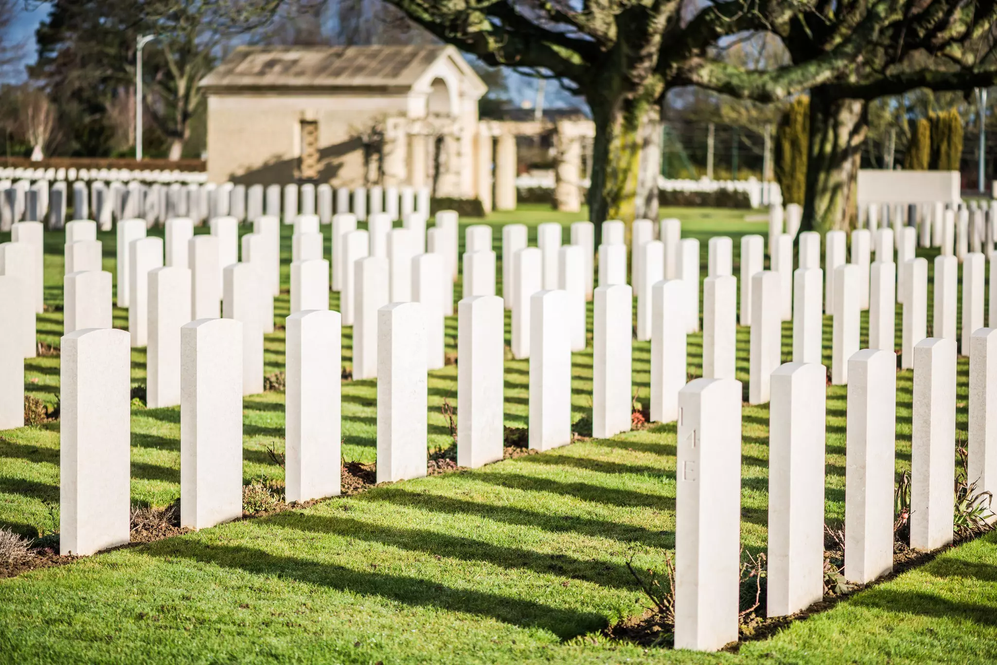 Rows of gravestones stand starkly on a sunny day at the Bayeux War Cemetery