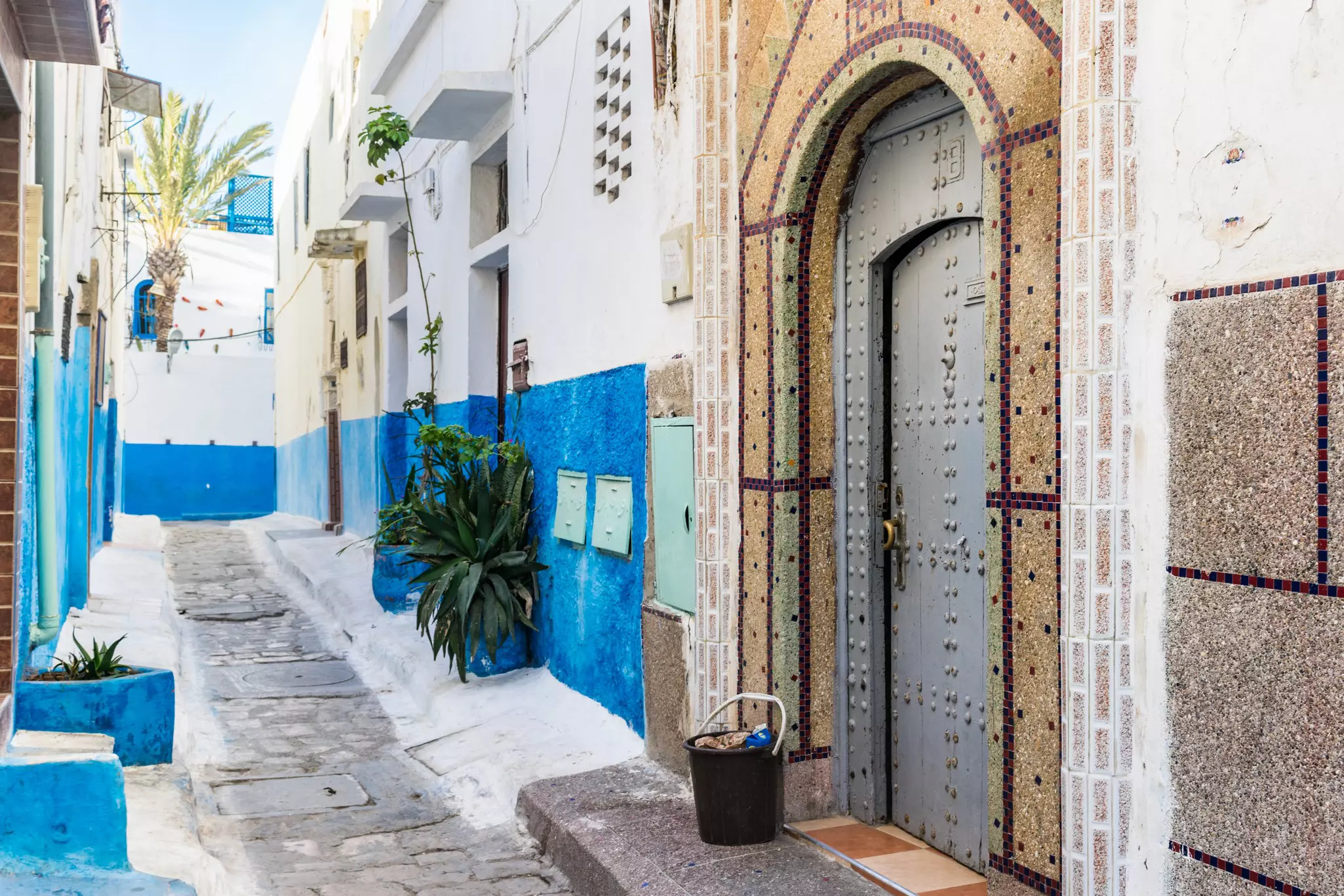 Painted blue and white walls and a decorative doorway in an alleyway