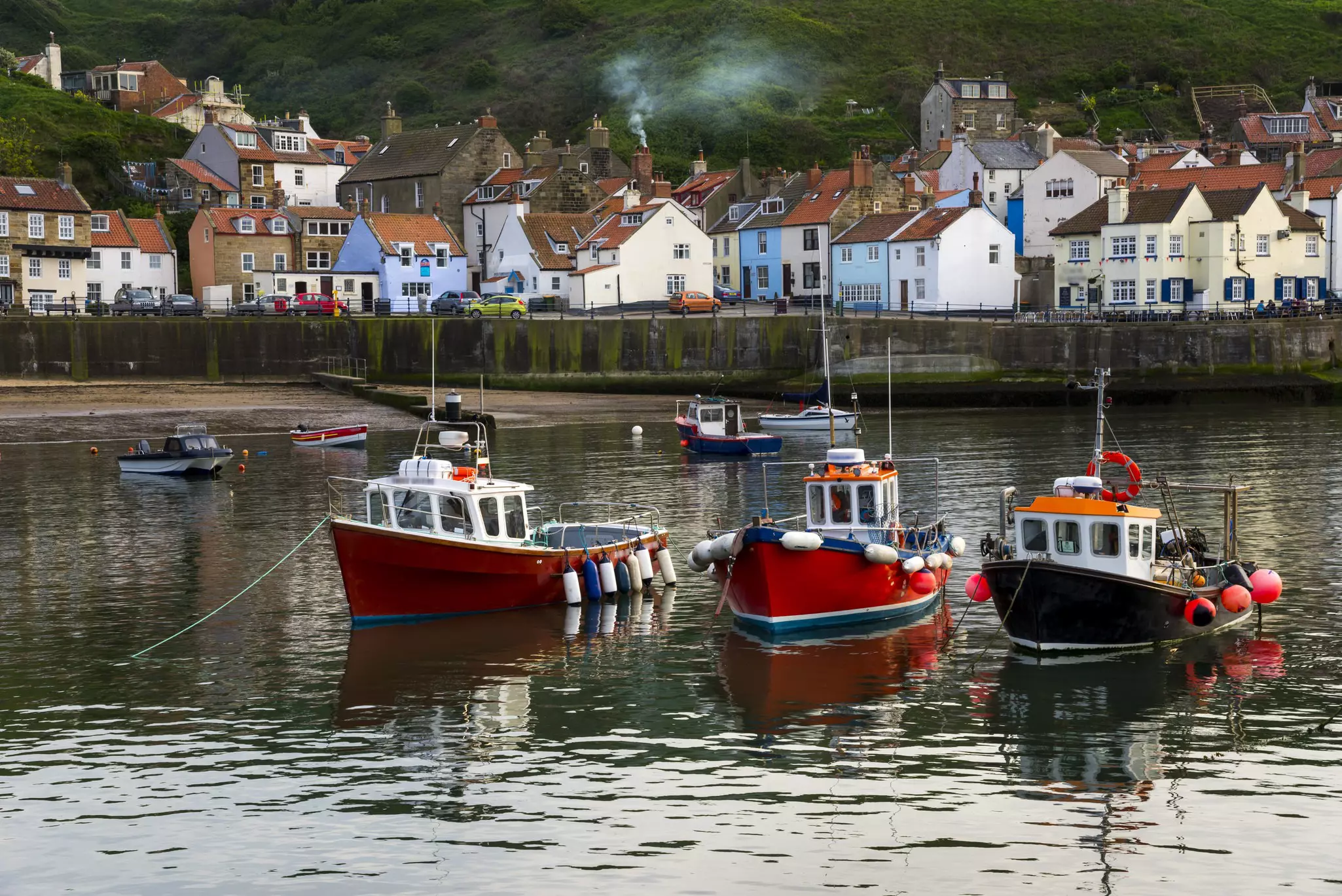 Fishing boats in a harbor in backed by traditional fishing cottages