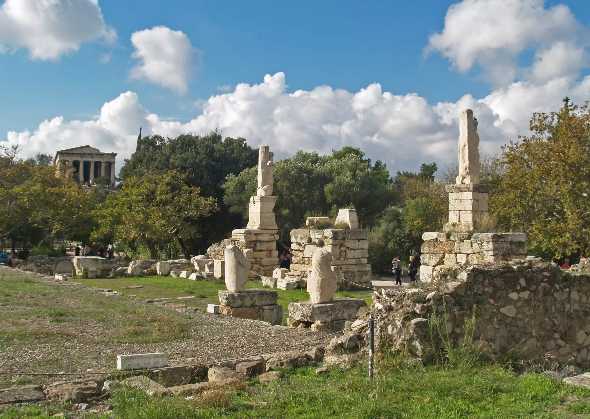 Tourists walk around the ruined statues and Temple of Hephaistos at ancient Agora in Athens.