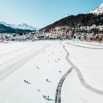 A mountain ski and snowboard resort with people out on a frozen lake