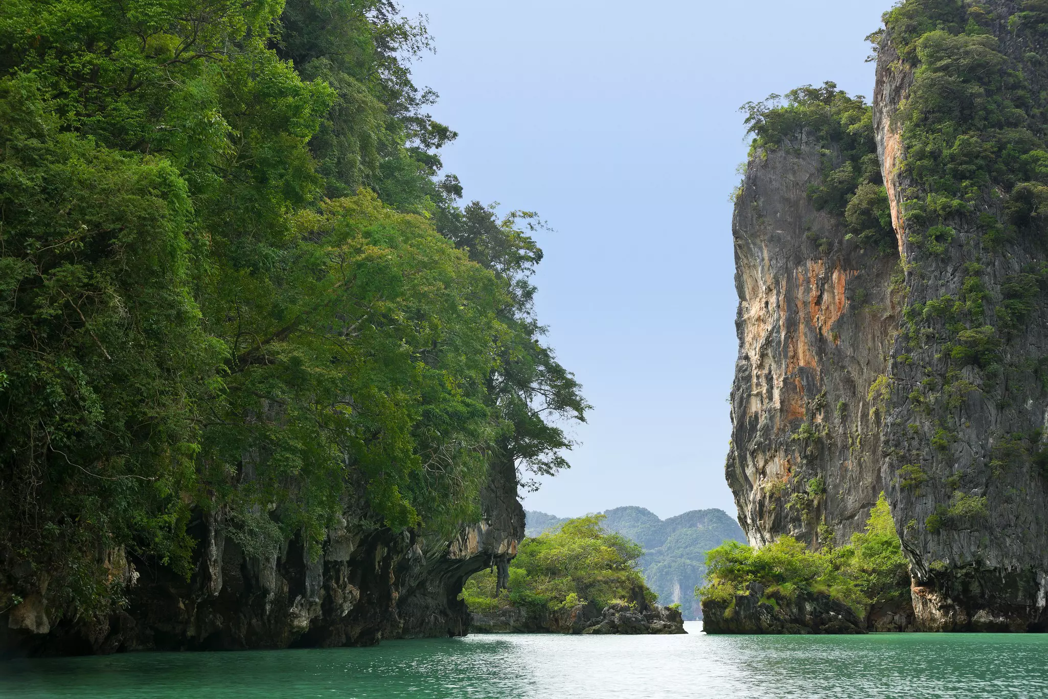 Islands of limestone, with cliffs hanging over green water.