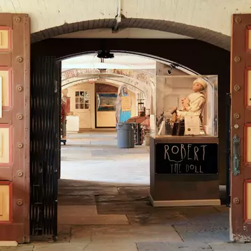 An antique doll is displayed in a case in an old fort turned into a museum.