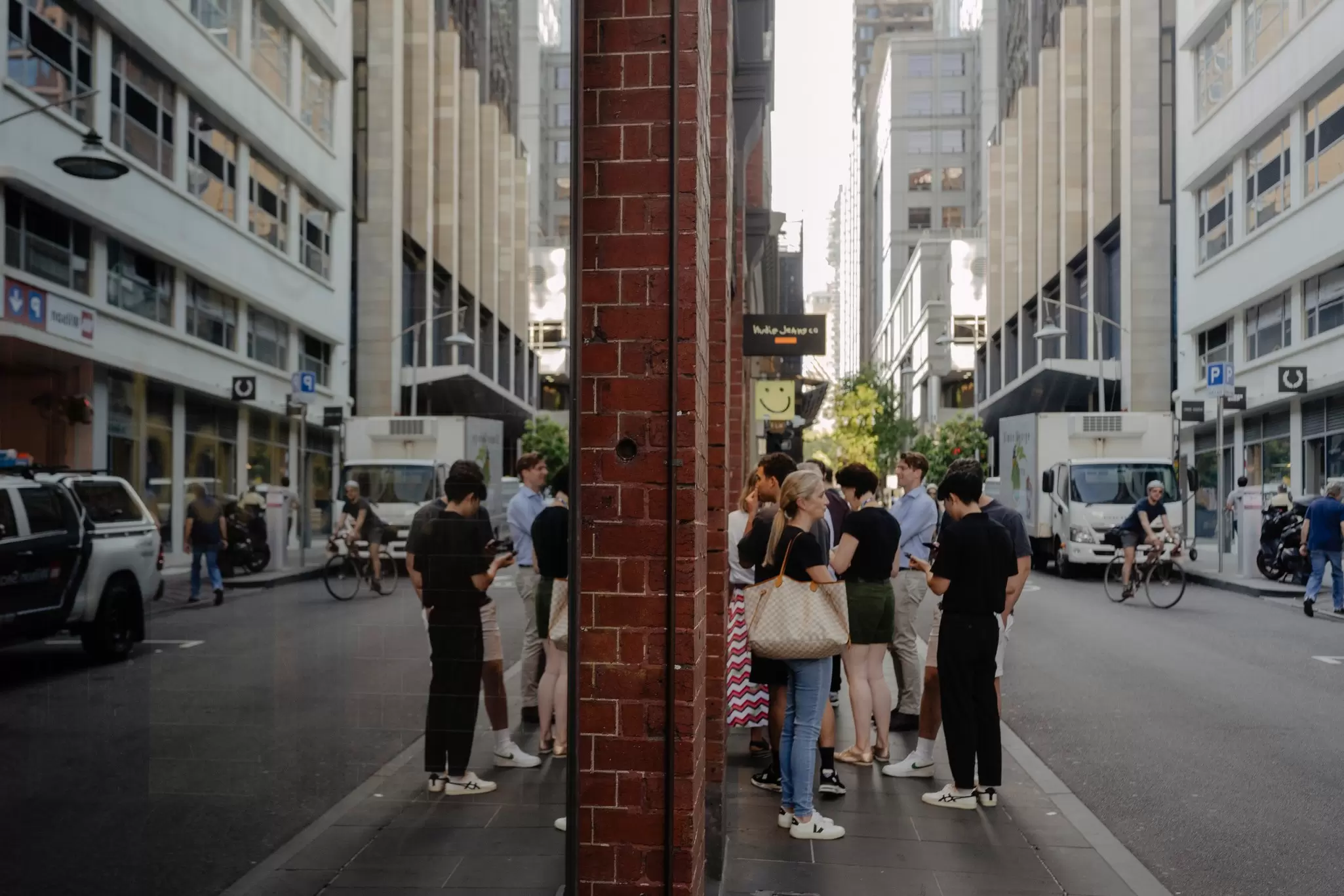 People queuing outside a store in a street in Melbourne's city center, a cyclist is passing them