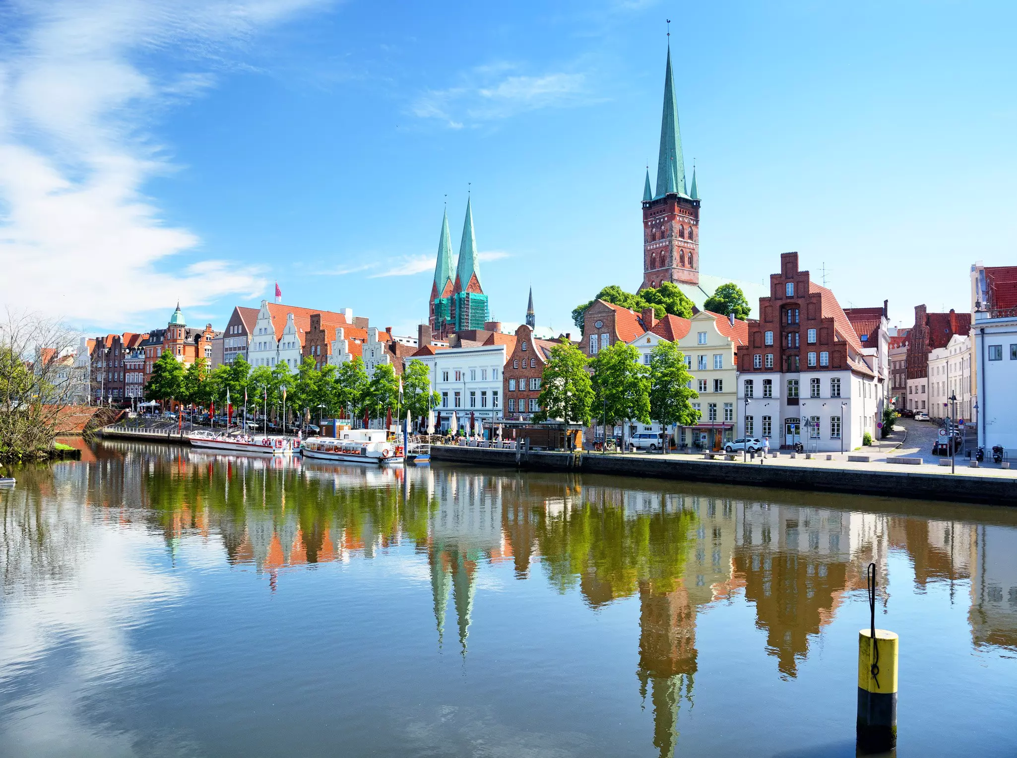 Wide shot of historic Old City buidings lining, and reflected in, a narrow waterway on a sunny day.