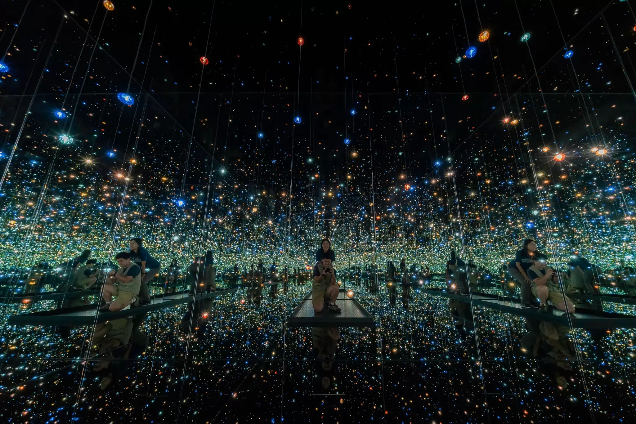 A room lined with mirrors and dimly lit by small lights; Yayoi Kusama's Infinity Mirror Rooms at The Broard Museum, Los Angeles