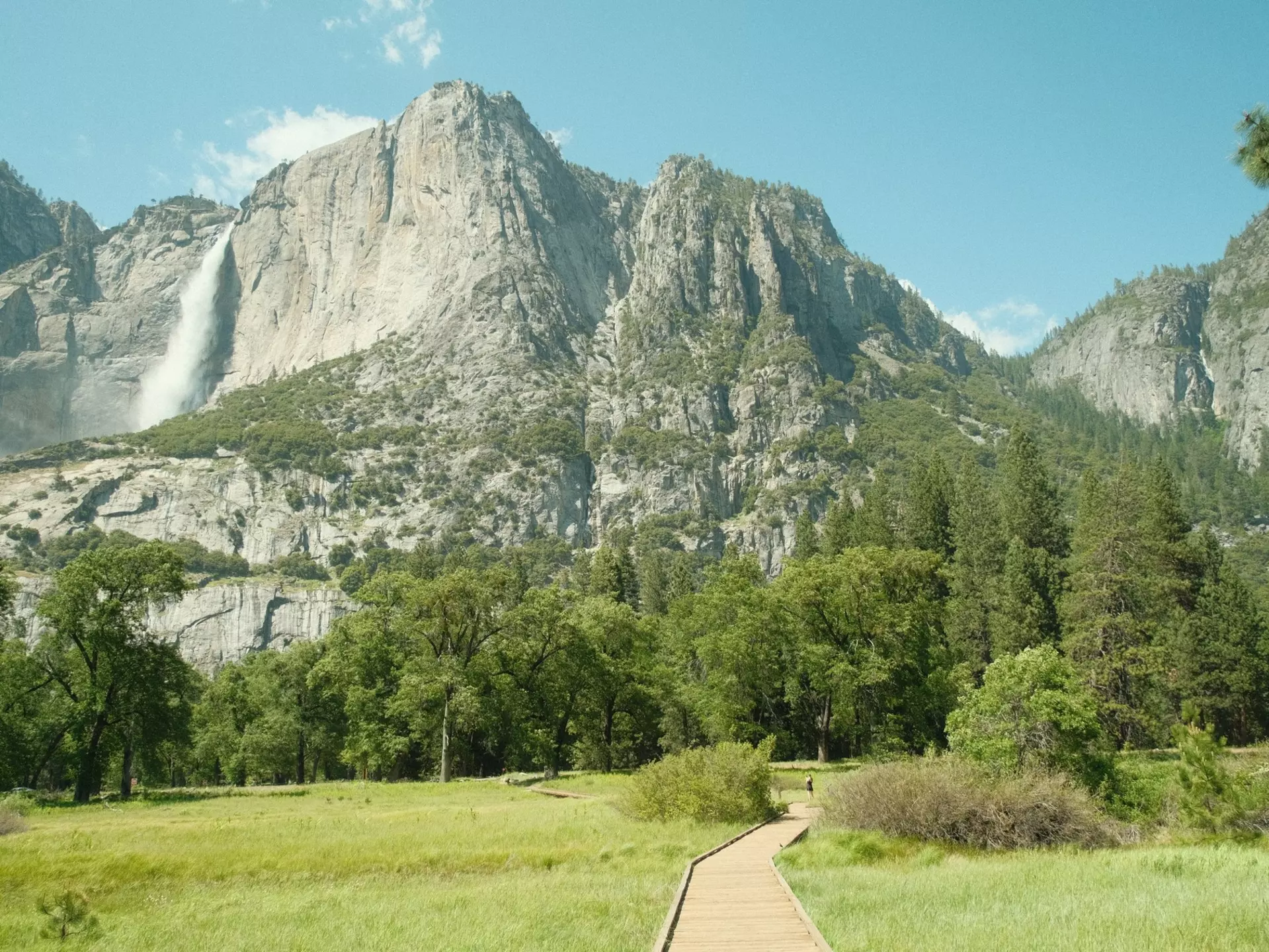 Yosemite National Park in California’s Sierra Nevada mountains green foliage on sunny day with waterfall,