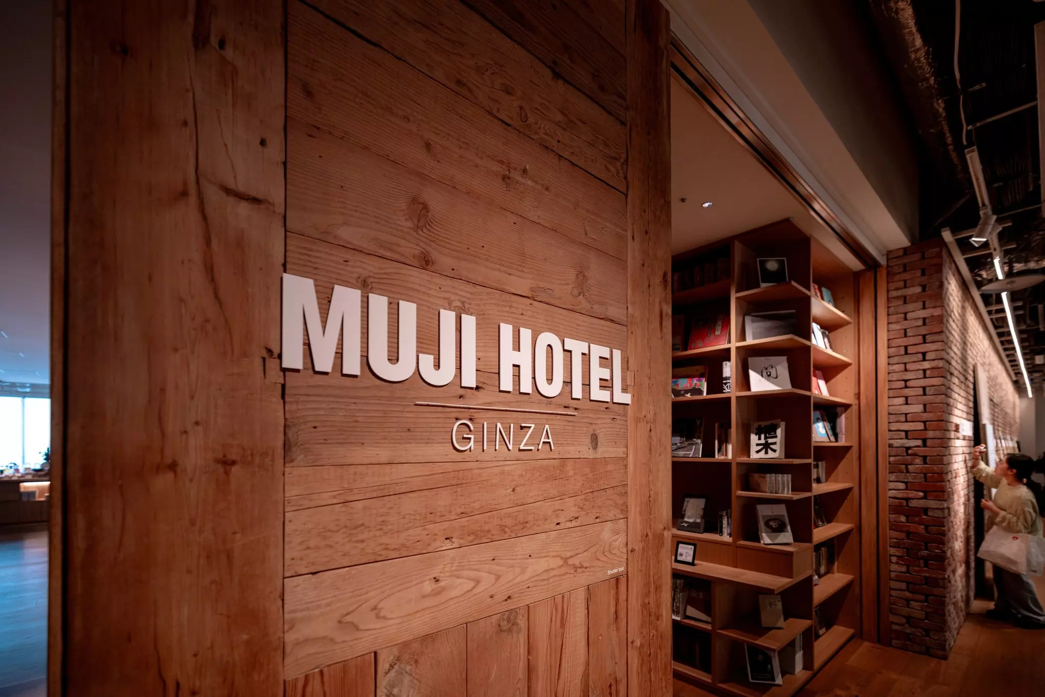 A wooden panel with a sign that read "Muji Hotel Ginza."