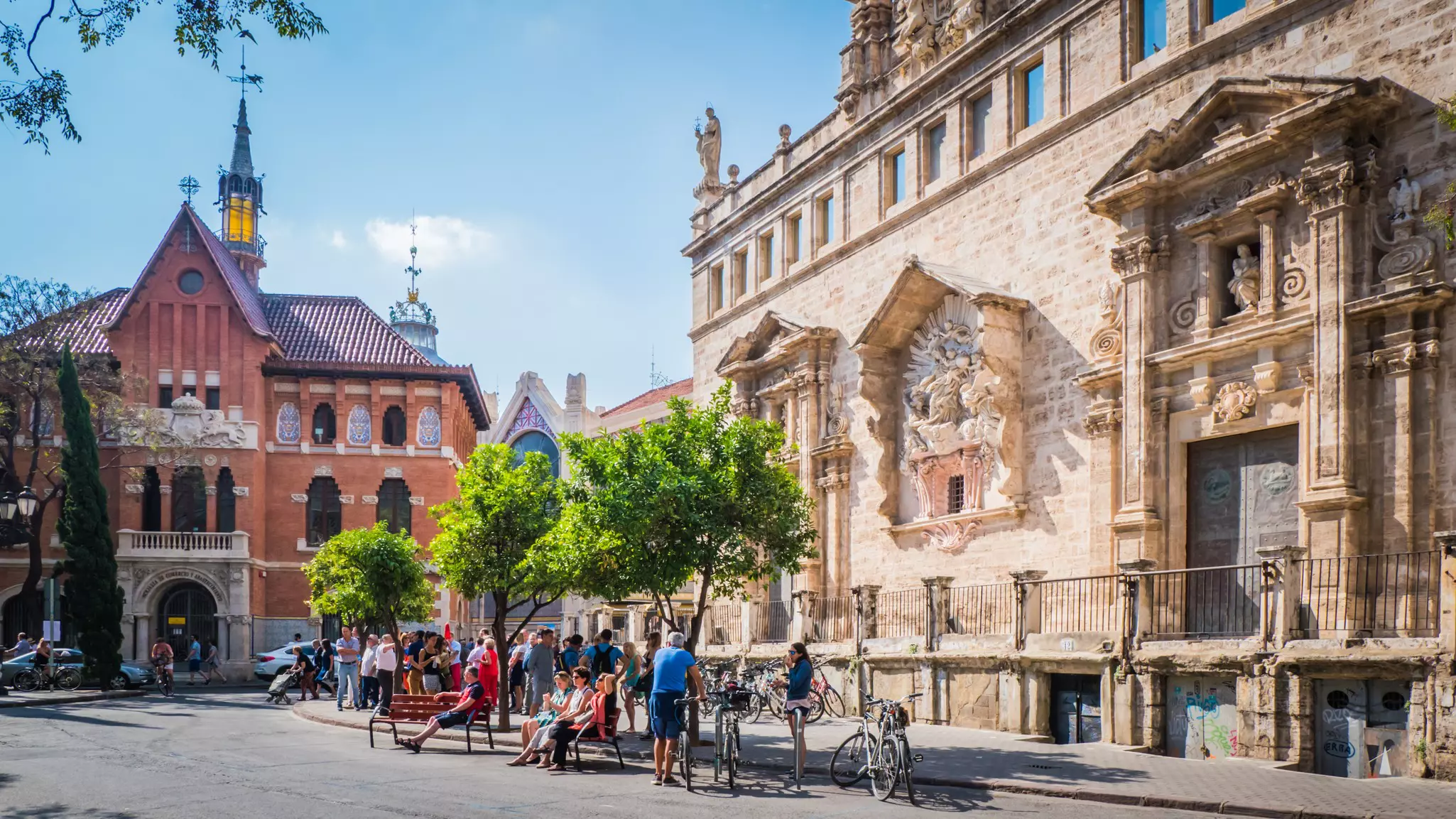 People and bikes moving around a street lined with historic buildings