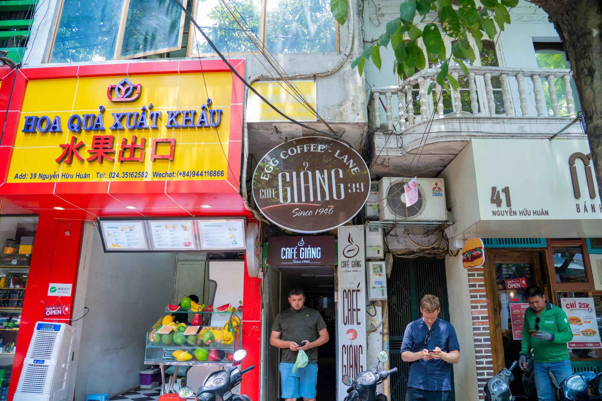 Three men standing outside city businesses in Vietnam.