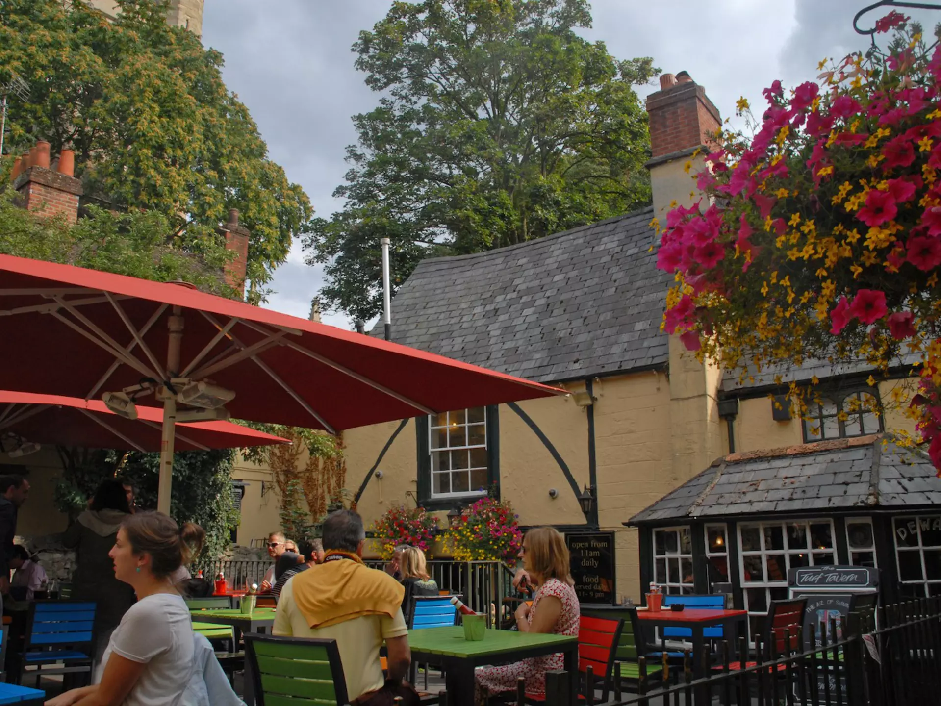 People enjoy drinks at outdoor tables in the beer garden of the Turf Tavern pub, Oxford, Oxfordshire, England, United Kingdom