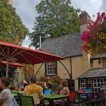 People enjoy drinks at outdoor tables in the beer garden of the Turf Tavern pub, Oxford, Oxfordshire, England, United Kingdom