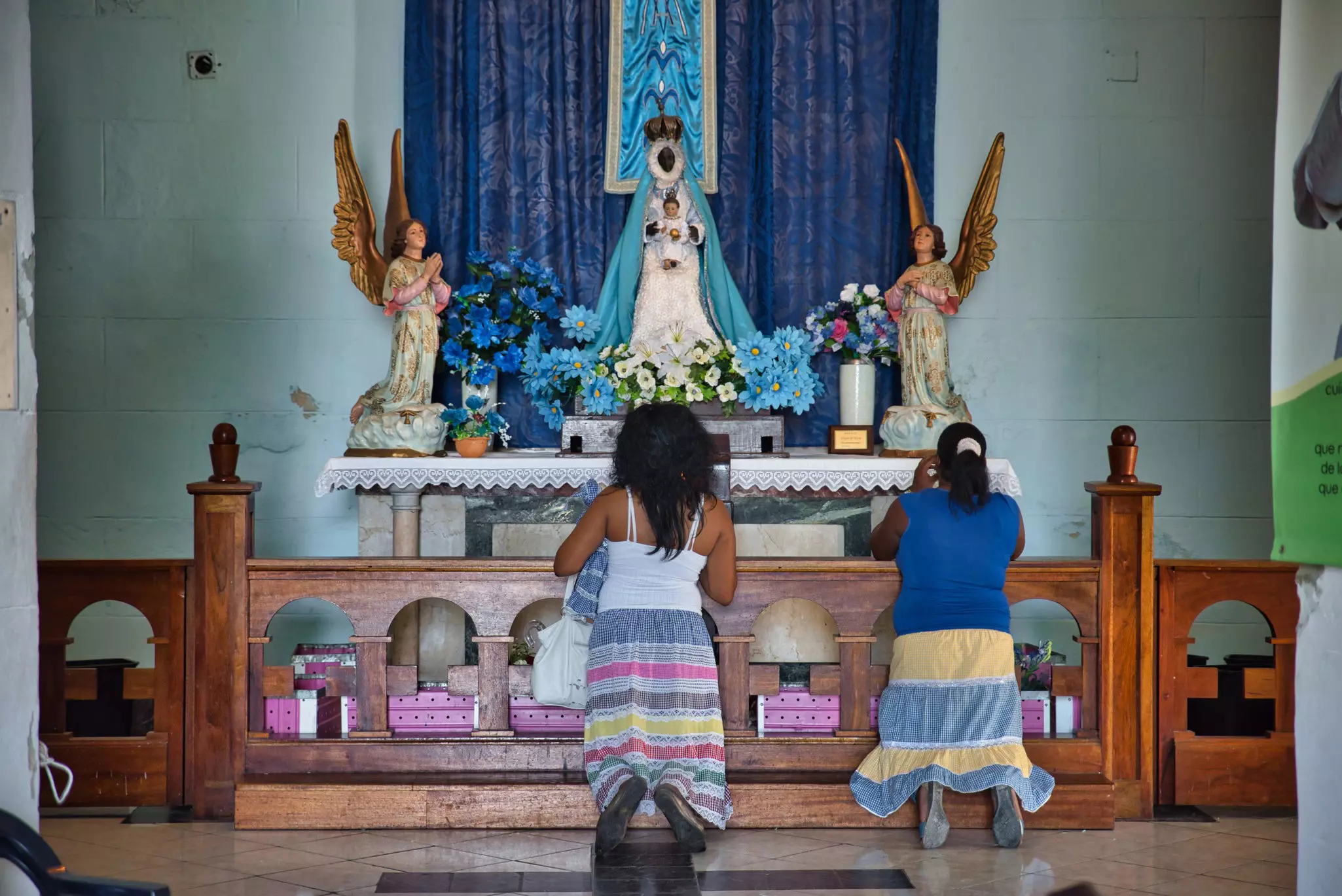 Women praying in front of the altar to Black Madonna at Our Lady of the Regla church
