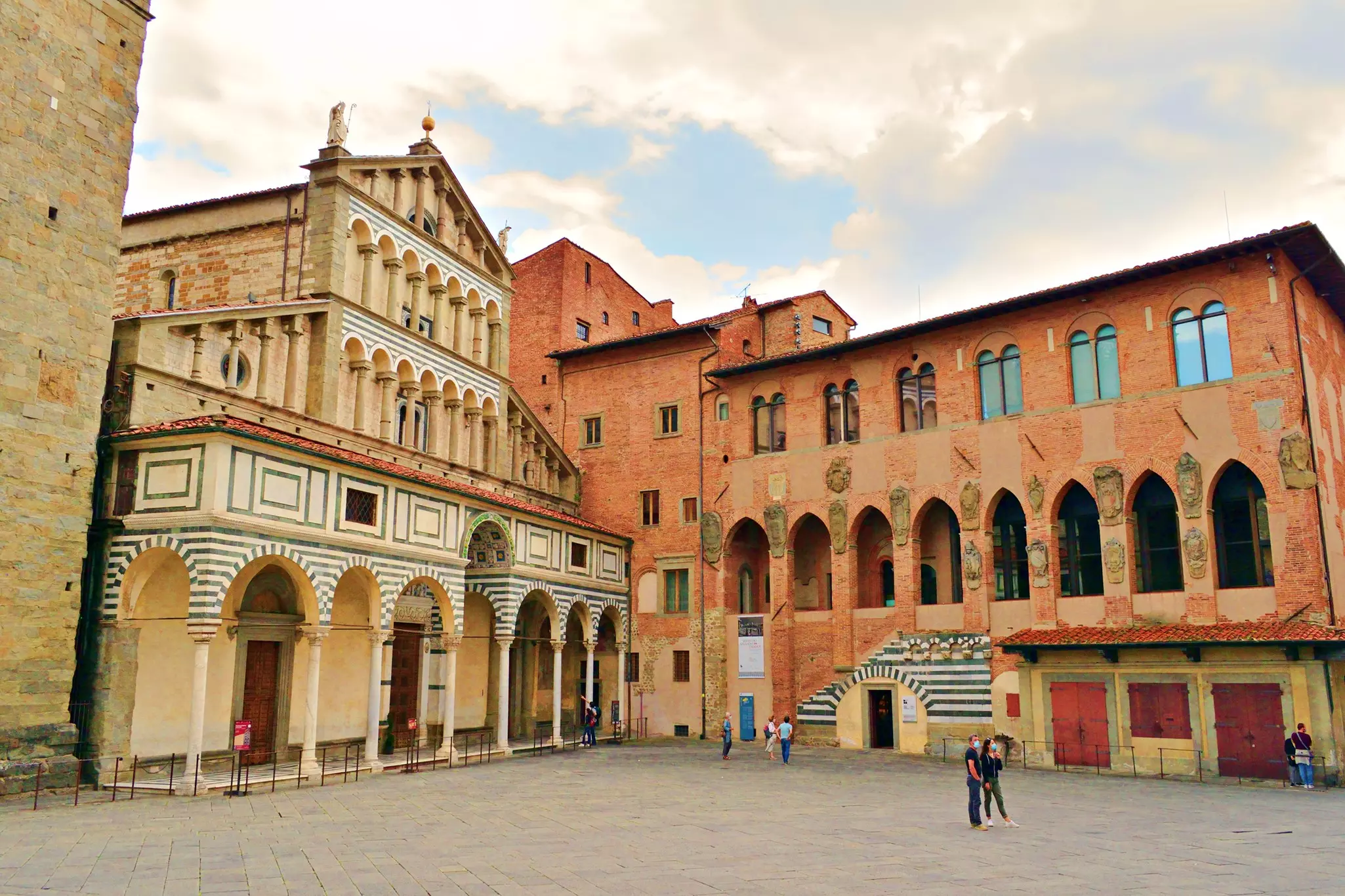 People are seen in large town square next to a medieval church