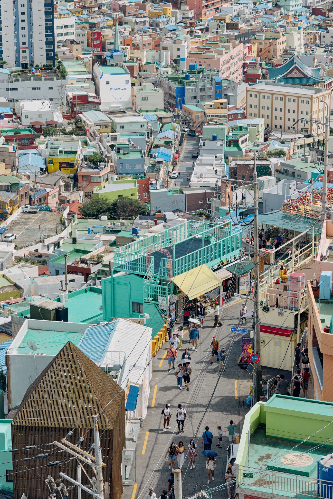 Pastel houses packed on a hillside in Gamcheon Culture Village, Busan, above a busy lane of visitors and shops