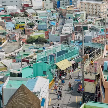 Pastel houses packed on a hillside in Gamcheon Culture Village, Busan, above a busy lane of visitors and shops