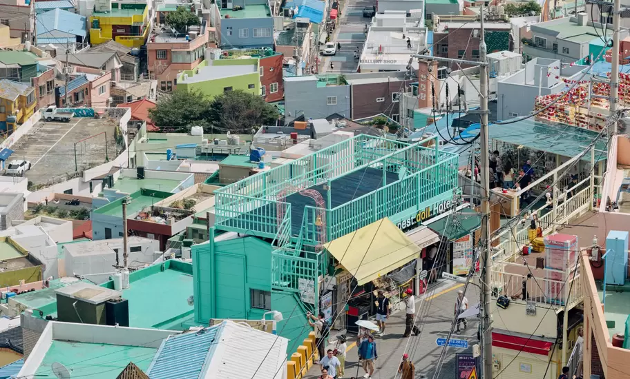 Pastel houses packed on a hillside in Gamcheon Culture Village, Busan, above a busy lane of visitors and shops
