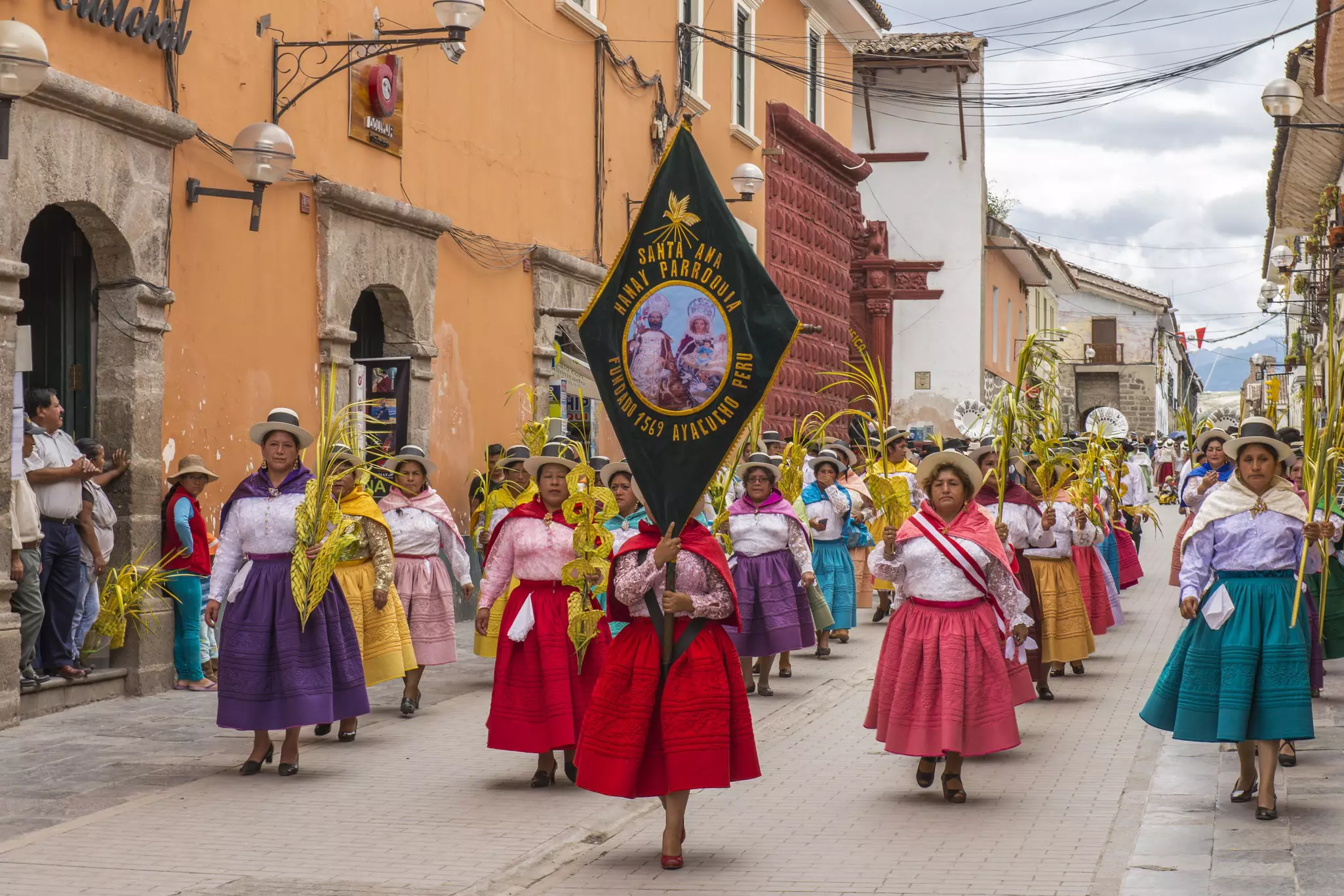 People with multicolored dresses and hats marching in a procession