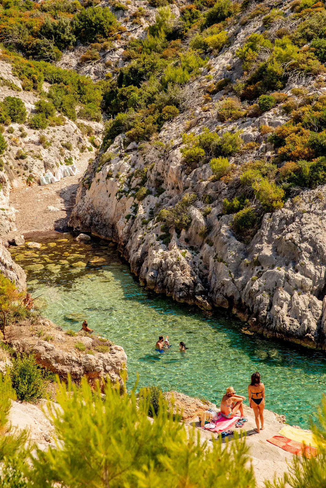 People in a tiny bay with clear green waters.