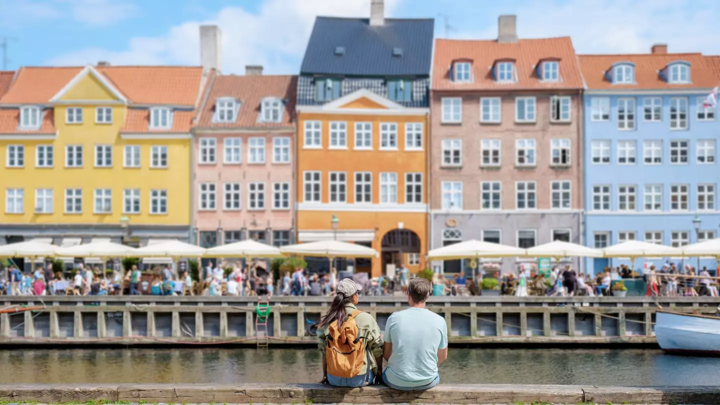 A couple sits on a wall by the water in Copenhagen, Denmark