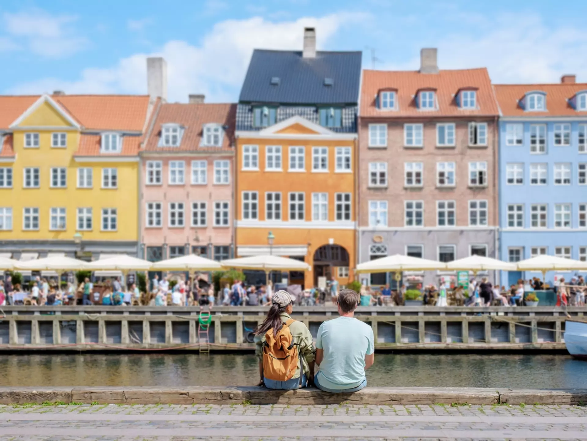 A couple sits on a wall by the water in Copenhagen, Denmark